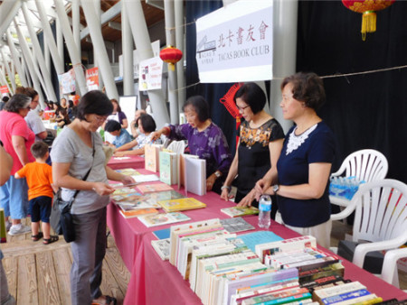 北卡書友會(huì)為游客寫書法和義賣中英文書籍。（美國《世界日?qǐng)?bào)》/王明心 攝）