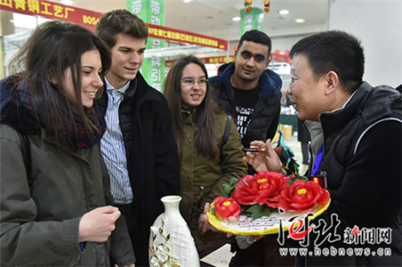 一位陶瓷商正向幾名來自石家莊四十二中的外國(guó)留學(xué)生介紹中國(guó)傳統(tǒng)節(jié)日飾品牡丹瓷。