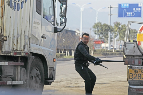 拔槍加油一名男子從油罐車上拔出加油槍，準(zhǔn)備給貨車加油